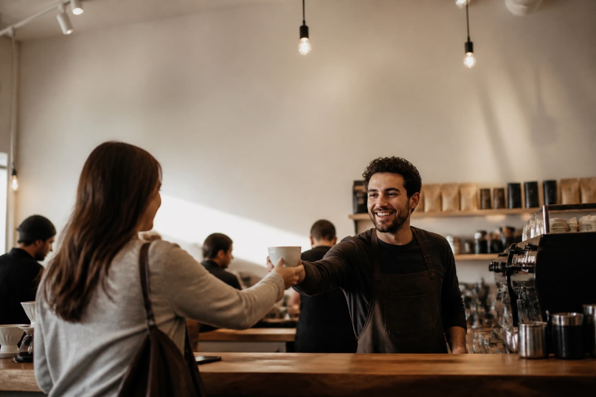 A barista handing a coffee to a regular across the counter