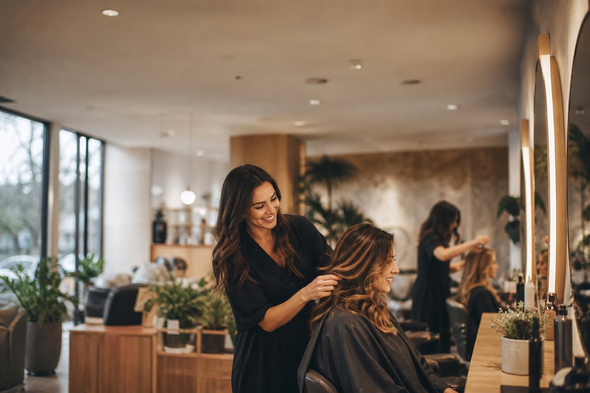 A stylist finishing a client's hair in a warm modern salon