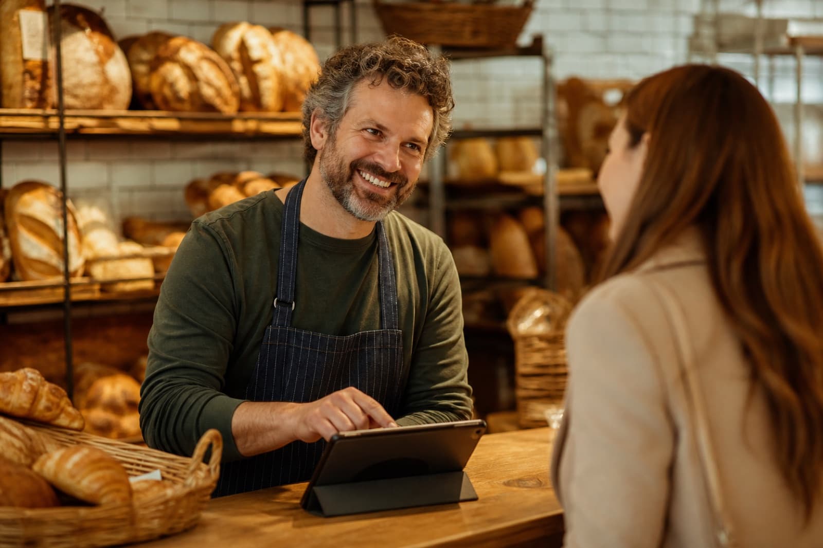 A baker greeting a returning regular at the bakery counter
