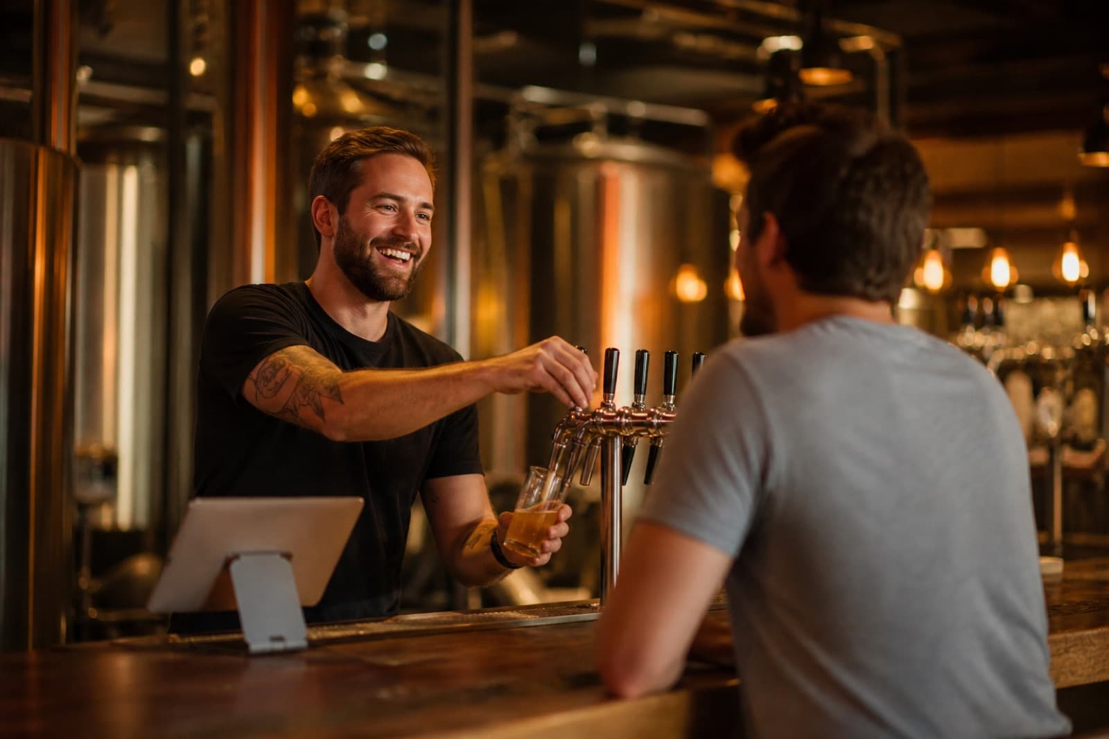 A bartender greeting a mug-club member while pulling a pour