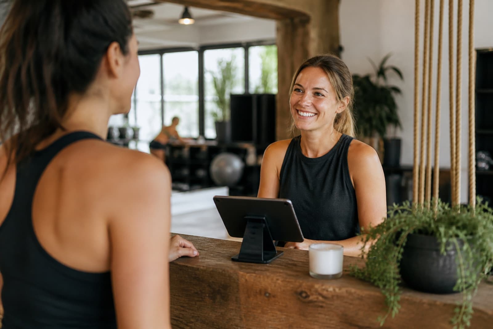 A studio staff member greeting a member checking in at the front desk