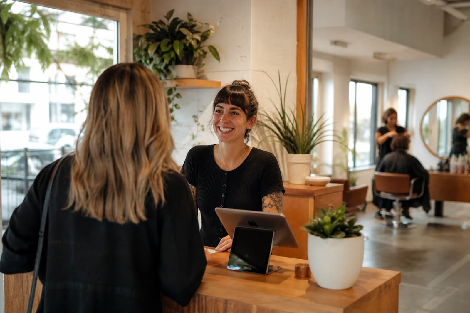 A salon front-desk stylist greeting a client at checkout